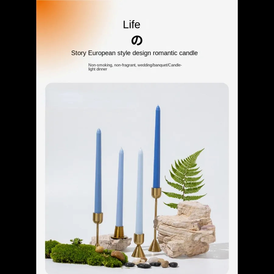 A set of gradient blue taper candles displayed on natural wood and moss in a minimalist setting.
