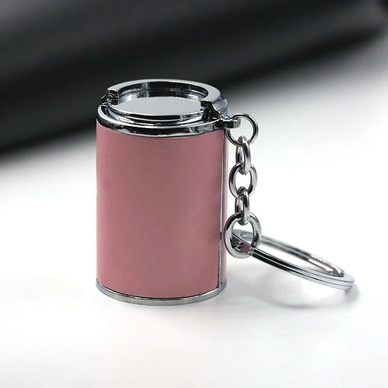 A small, cylindrical coin holder keychain with a pink body and silver metal hardware.