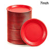 A stack of red 7-inch disposable paper plates, with one plate lying separately.