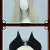 A close-up of a black bat simulation headpiece with feathery ears worn on a light blonde wig.