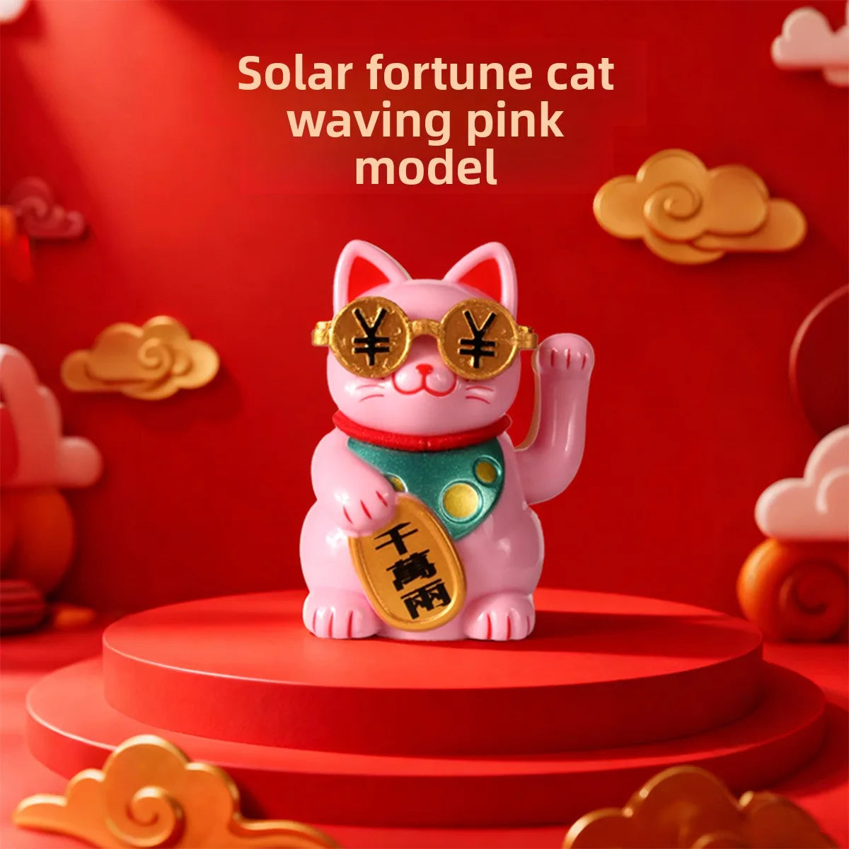 A pink cat ornament with gold accents and a green collar is displayed on a red circular base.