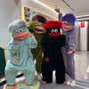 Three people wearing fuzzy monster onesies pajamas in various colors standing indoors