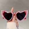 A pair of heart-shaped sunglasses decorated with pink pearls and the word bride to be