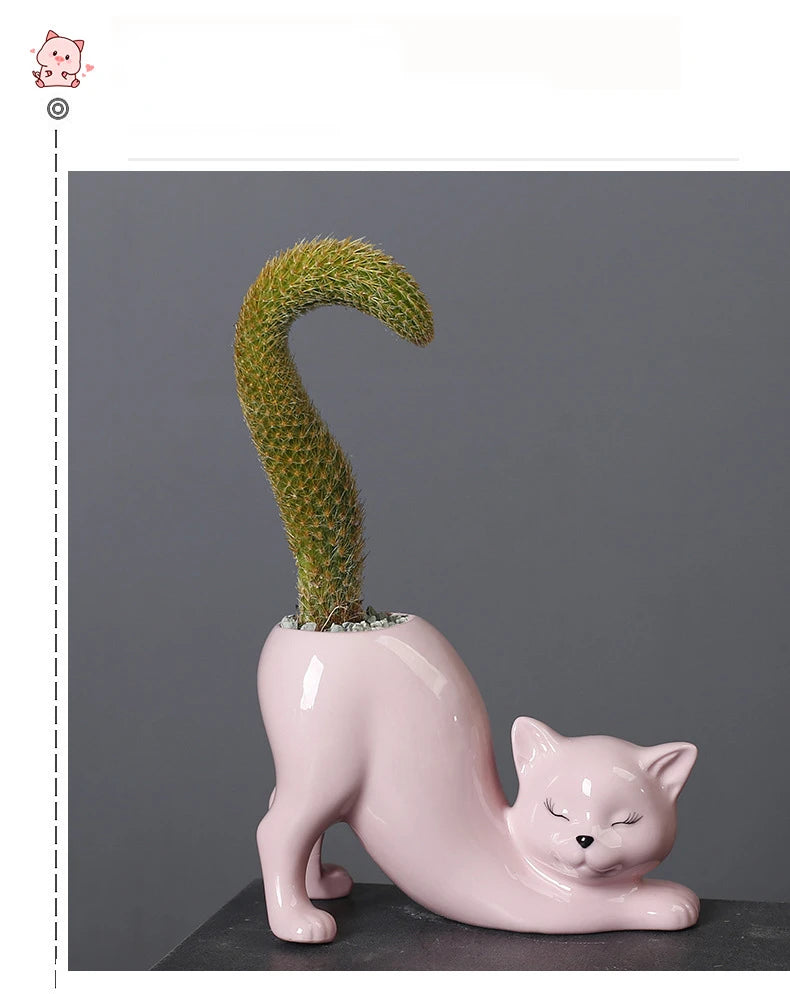 A pink ceramic cartoon cat planter shaped like a feline, holding a green succulent plant with a curved tail.