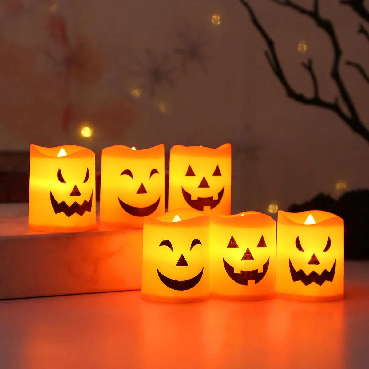 A set of six glowing orange Halloween-themed LED candles arranged on a white surface.