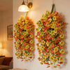 A vibrant hanging vine of artificial eucalyptus and violet pansy flowers on a white wall.