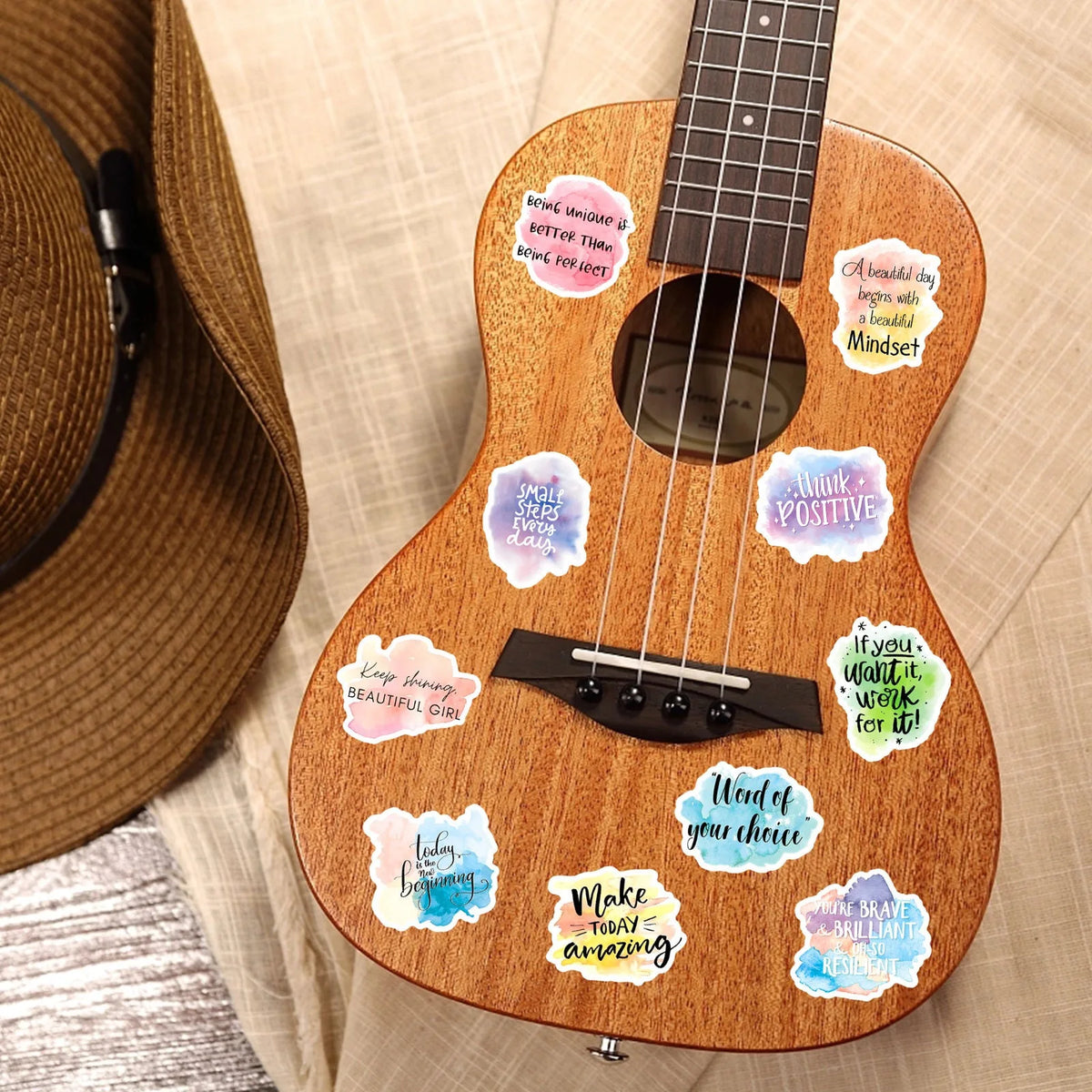 A wooden acoustic guitar decorated with inspirational messages and stickers on the body