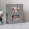 A gray linen-covered photo album with two square photo pockets displaying a couple.