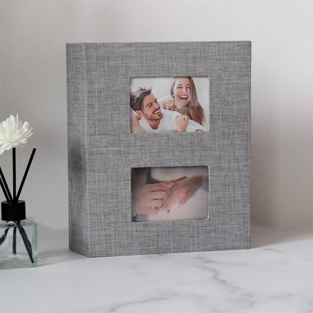 A gray linen-covered photo album with two square photo pockets displaying a couple.