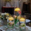Glass vase filled with pink and white flowers and floating LED tealight candles