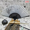 An elegant vintage Chinese folding hand fan with black and white stripes rests on a wooden stand.