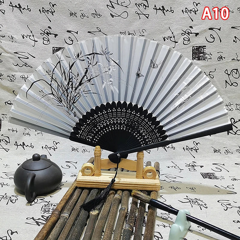 An elegant vintage Chinese folding hand fan with black and white stripes rests on a wooden stand.
