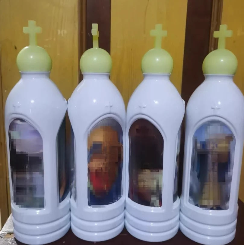 A set of four white glow-in-the-dark holy water bottles with green caps displayed against a wooden background.