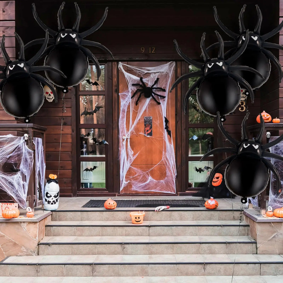 Sechs schwarze spinnenförmige Aluminiumballons schmücken eine Holzpforte für Halloween.