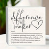 A white wooden sign with black script that reads difference maker and a definition below.
