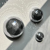 A set of three mirrored disco ball half-spheres casting light patterns on a gray wall.