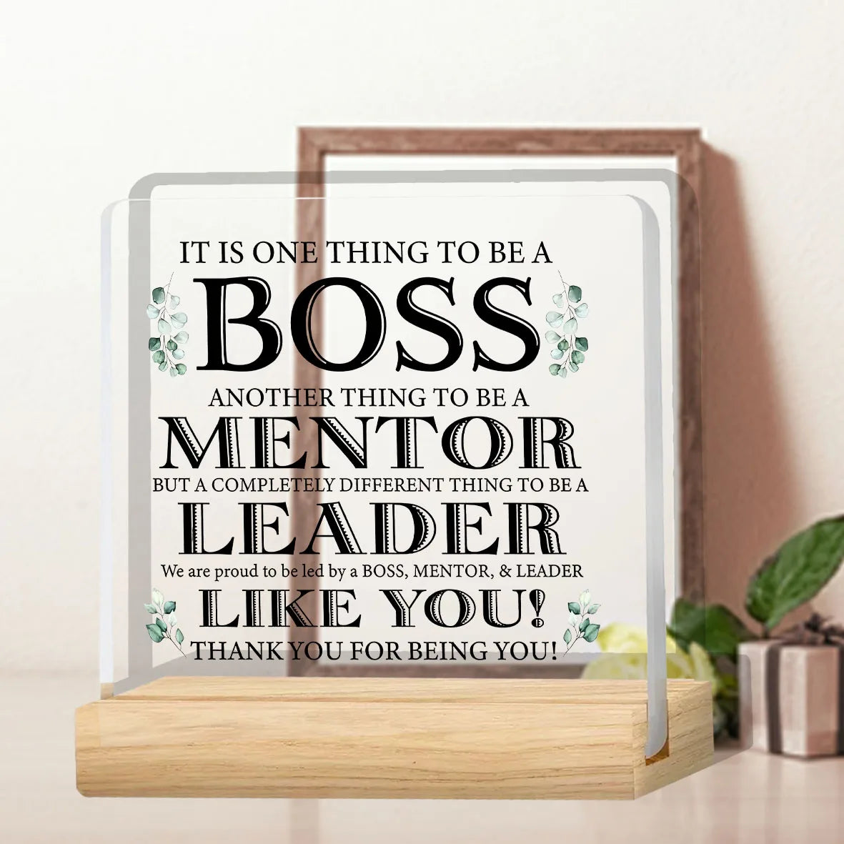 A clear acrylic plaque with text appreciating a boss, mentor, and leader, displayed on a wooden base.