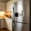 A stainless steel refrigerator door featuring a clear acrylic magnet and a black magnetic holder.