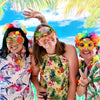 Three women smiling outdoors wearing colorful Hawaiian themed sunglasses and tropical floral shirts