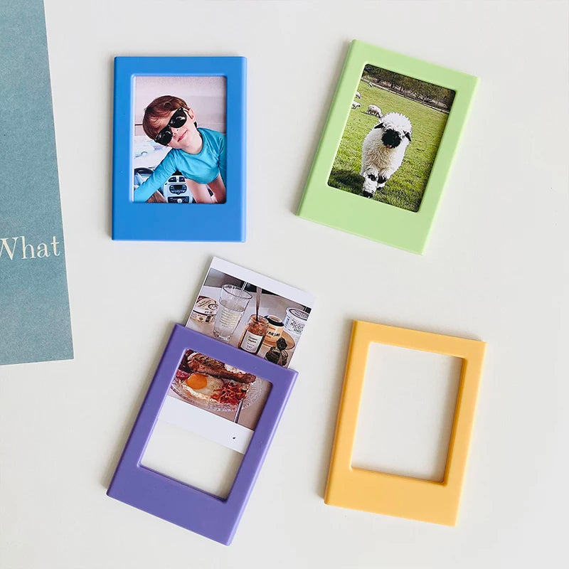 A collection of four magnetic photo frames in blue, green, purple, and yellow, displaying small photographs.