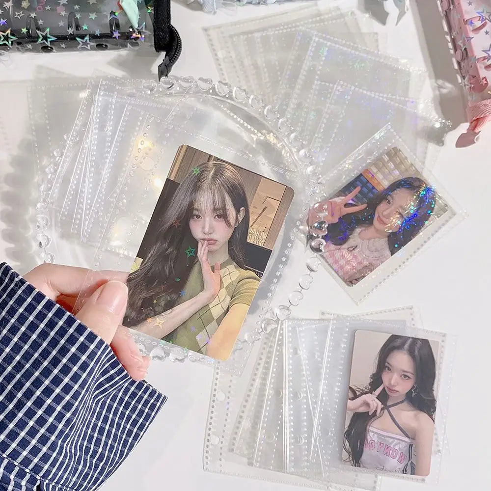 A hand holds a clear glitter star card binder containing several photo cards and stickers.