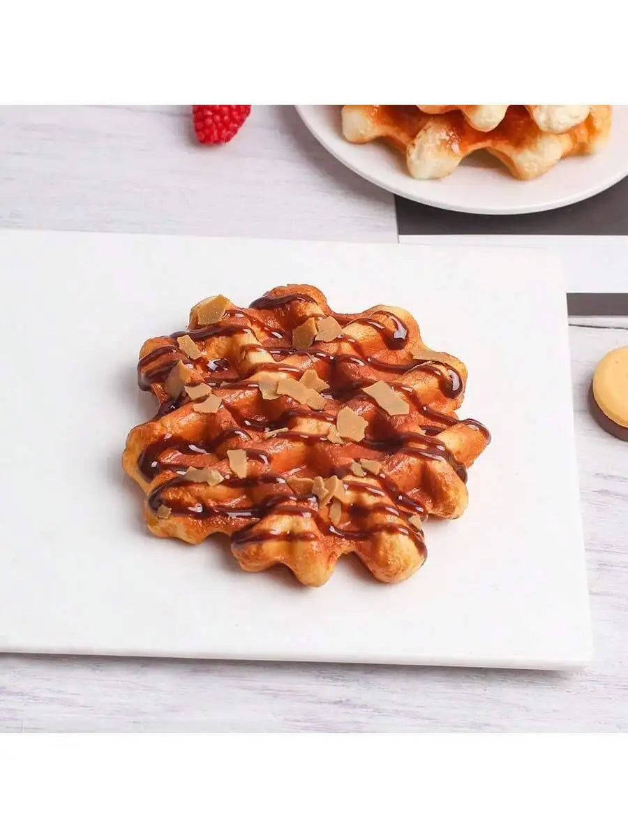 A golden waffle drizzled with syrup and topped with chopped nuts on a white plate.