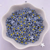 A pile of small, gray resin flower gems with yellow centers in a white dish.
