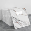 A stack of rectangular faux marble self-adhesive wall tiles featuring white and gray veining on a gray background.
