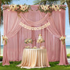 A pink chiffon backdrop curtain decorated with floral garlands and a birthday banner, set up for an event.