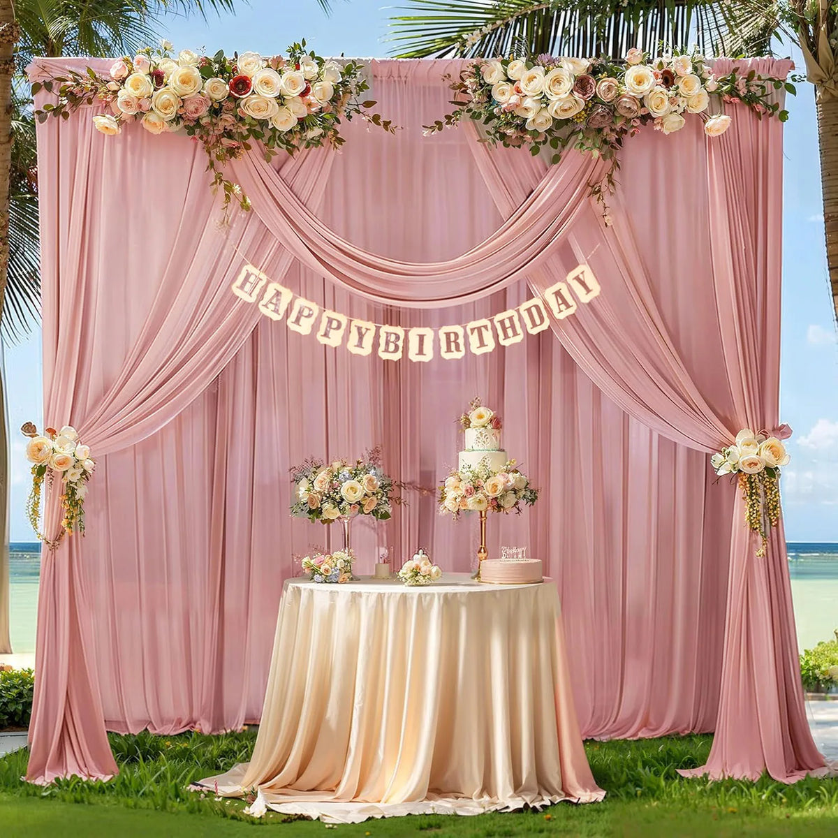 A pink chiffon backdrop curtain decorated with floral garlands and a birthday banner, set up for an event.