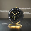 A black minimalist alarm clock with a gold-colored dial and an elliptical base, showing the time.