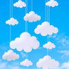 White felt clouds are hanging from strings against a bright blue sky.