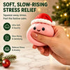 A hand holds a pink squishy stress relief toy with a Santa hat, set against a blurred Christmas background.