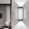 A modern LED crystal outdoor wall sconce mounted on a white wall, casting a bright light.