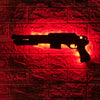 A silhouette of a gun-shaped light fixture mounted on a red brick wall.