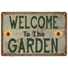 A vintage metal tin sign with distressed paint that reads Welcome to The Garden in green lettering.