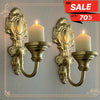 A set of two vintage wrought iron wall-mounted candle holders with white pillar candles.