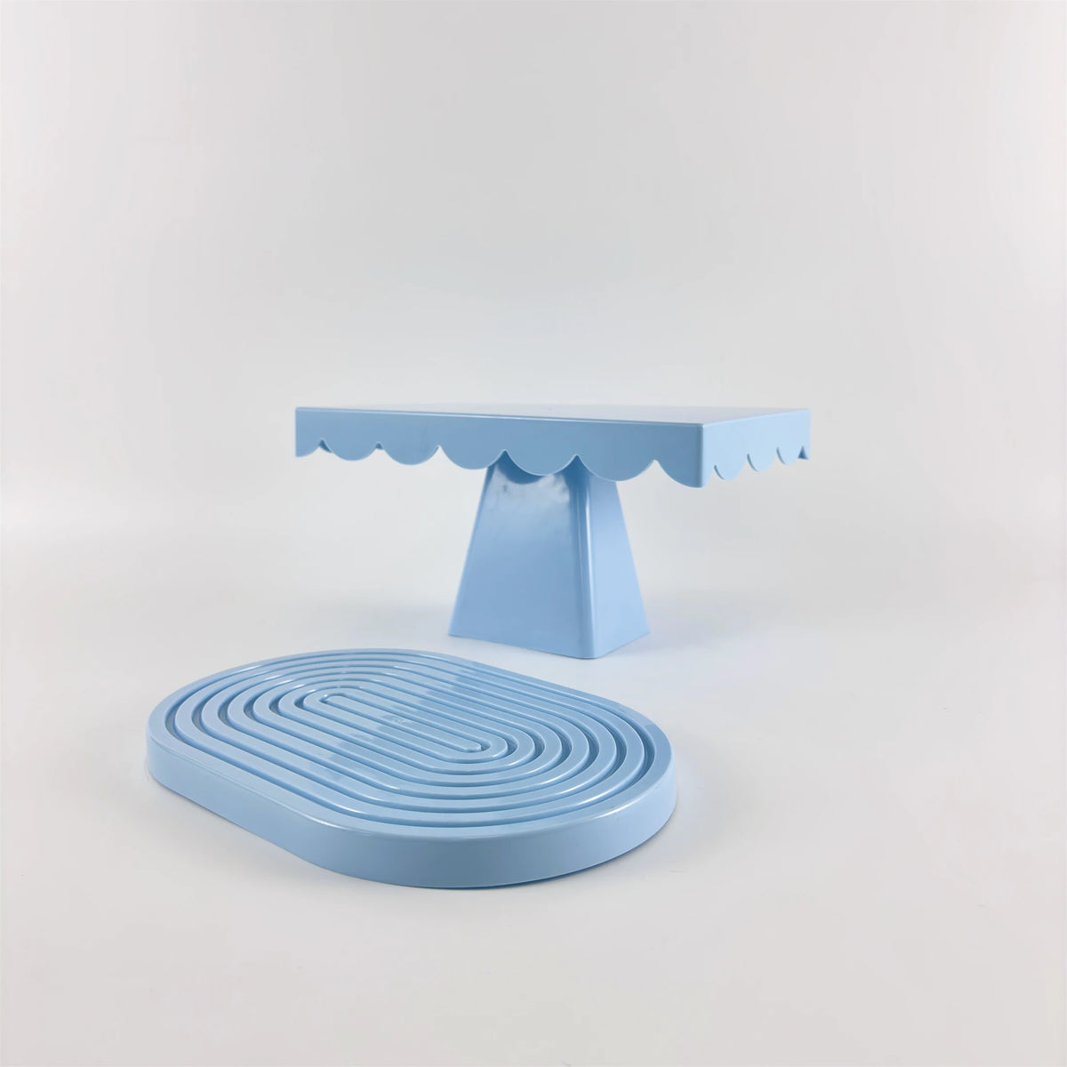 A light blue cupcake stand with a scalloped top and a matching round stand.