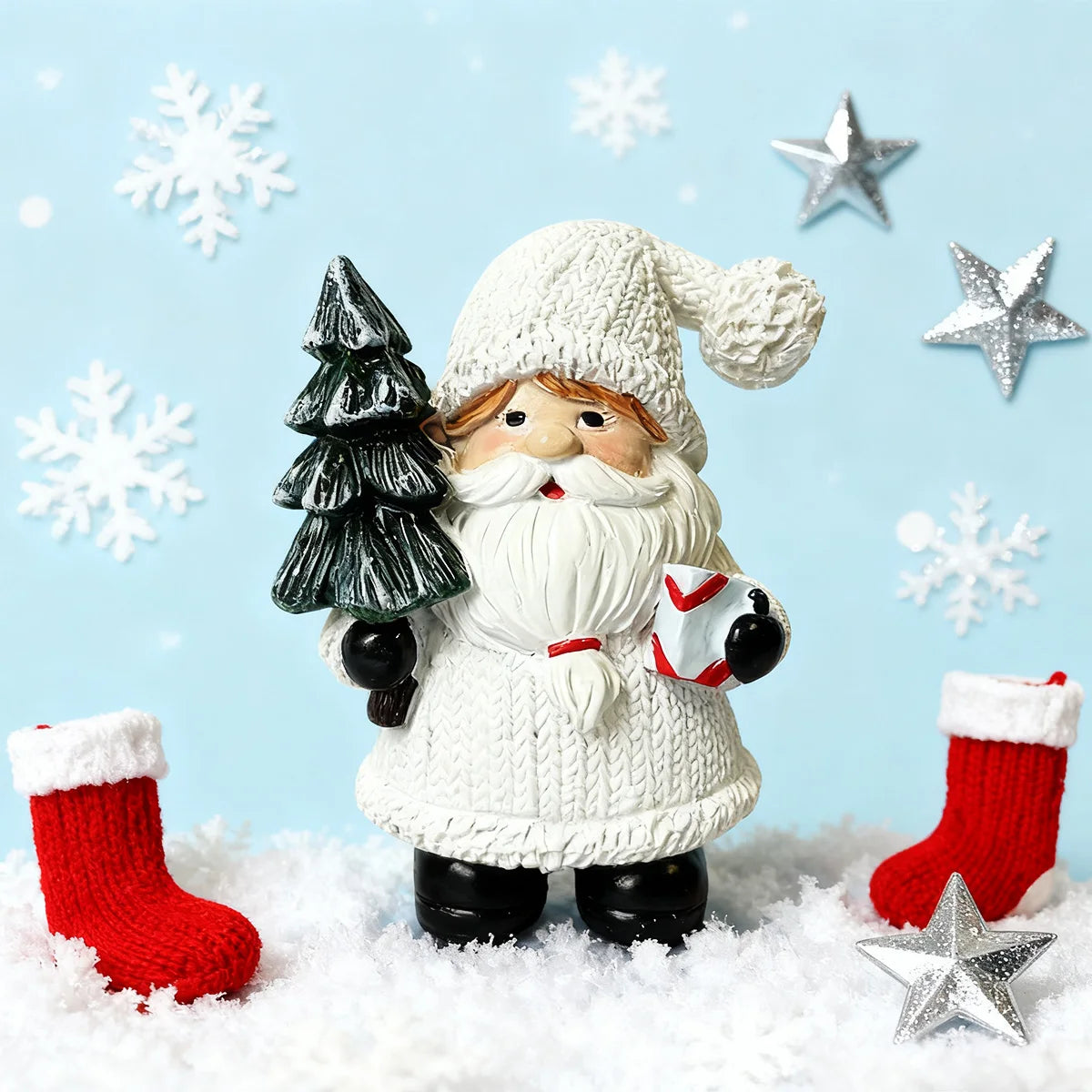 Figura de Papá Noel con barba y sombrero blanco junto a un árbol verde rodeado de copos de nieve en una superficie nevada.
