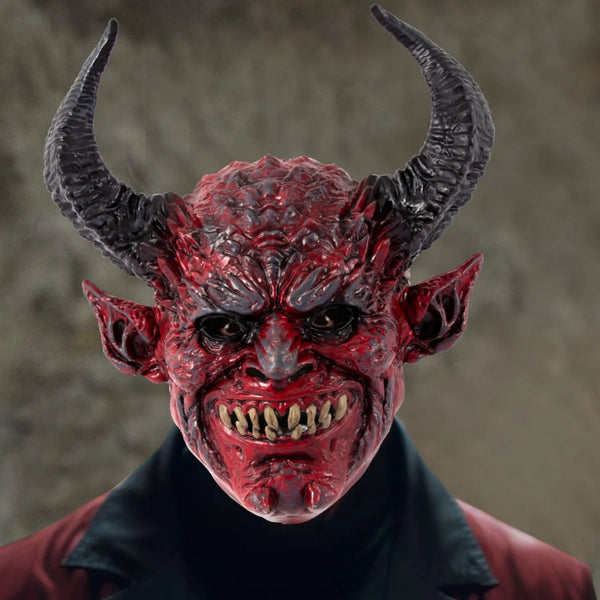 A realistic, grotesque devil head mask with horns and a fierce expression, painted in deep red and black tones.