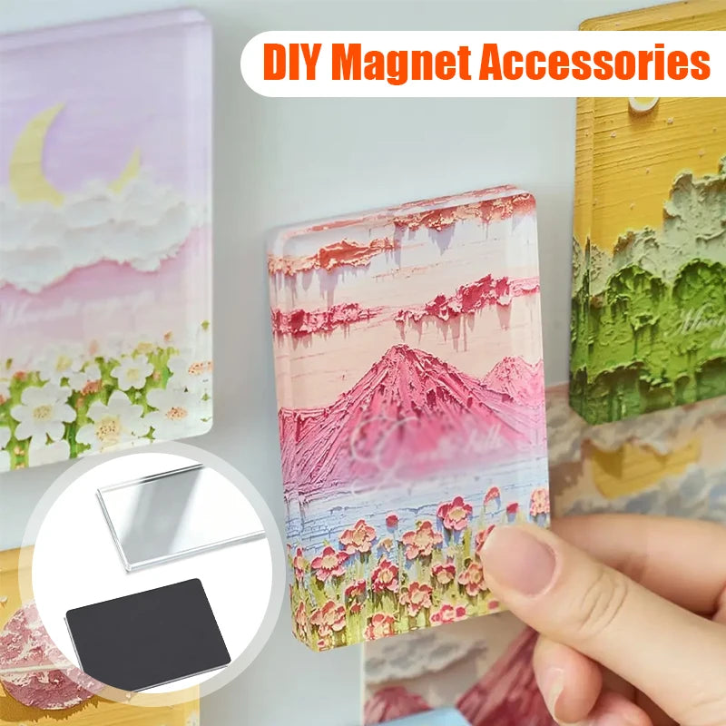 A hand holds a pink and purple acrylic photo magnet with a mountain landscape design.