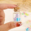 A hand holds a glass vial with a cork stopper and a colorful gemstone inside.