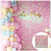 A pink glitter square wall backdrop decorated with clusters of pastel pink and blue balloons and the text Lets Party