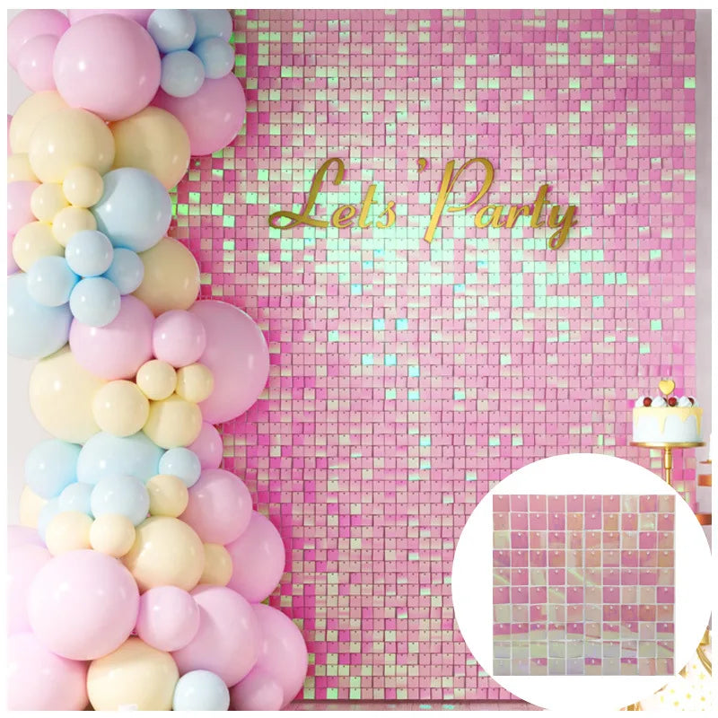 A pink glitter square wall backdrop decorated with clusters of pastel pink and blue balloons and the text Lets Party
