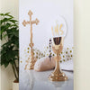 A gold-toned cross and a goblet are displayed on a silver backdrop for a party photo booth.