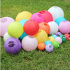 A collection of colorful decorative paper lanterns in various sizes and shades scattered on green grass.