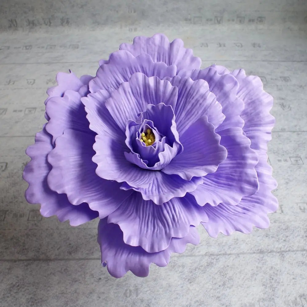 A purple silk foam rose flower with layered petals is shown against a light gray background.