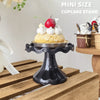 A mini size cupcake stand displaying a single decorated cupcake with cream and a red berry on a wooden surface.