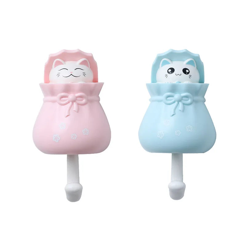 A pair of pink and light blue cartoon cat wall hooks for organization.