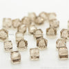 A collection of square cut glass crystal beads for jewelry making scattered on a white surface.